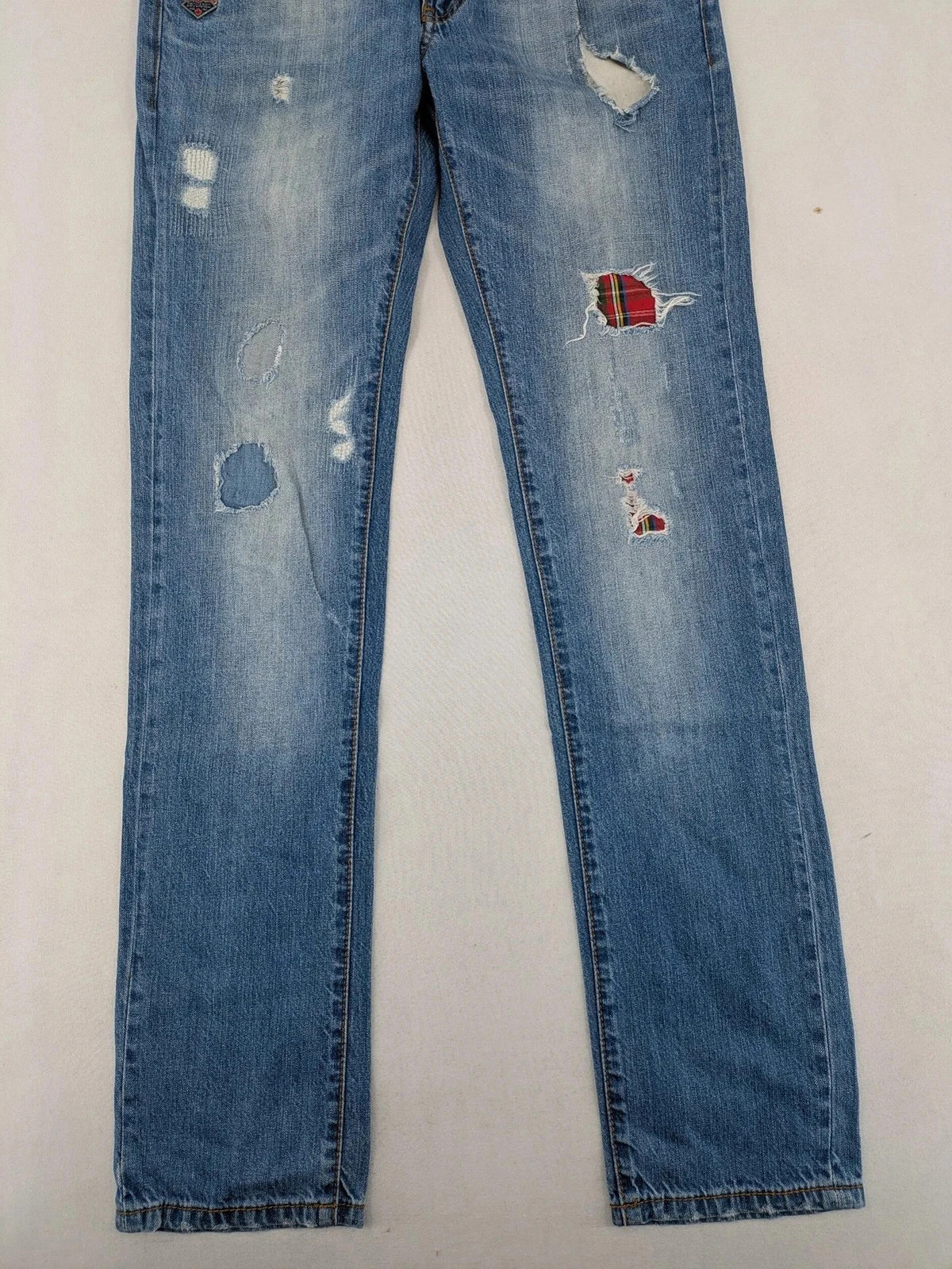 Andrew & Angel blue straight jeans distressed with red tartan patches and worn details.