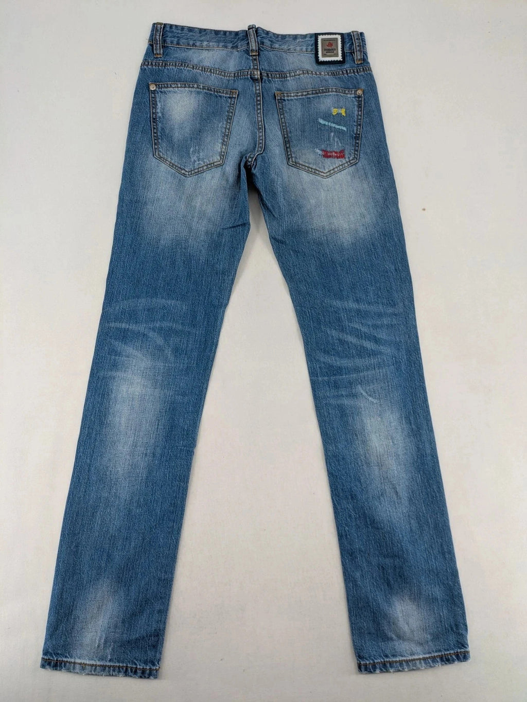 Andrew & Angel blue straight jeans distressed with red tartan patches and worn details.