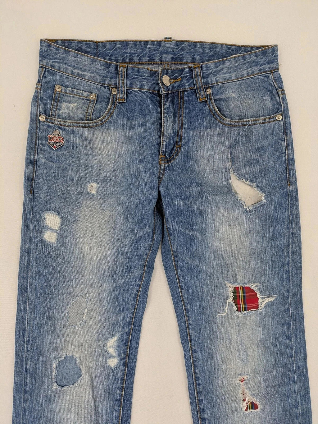 Andrew & Angel blue straight jeans distressed with red tartan patches and worn details.