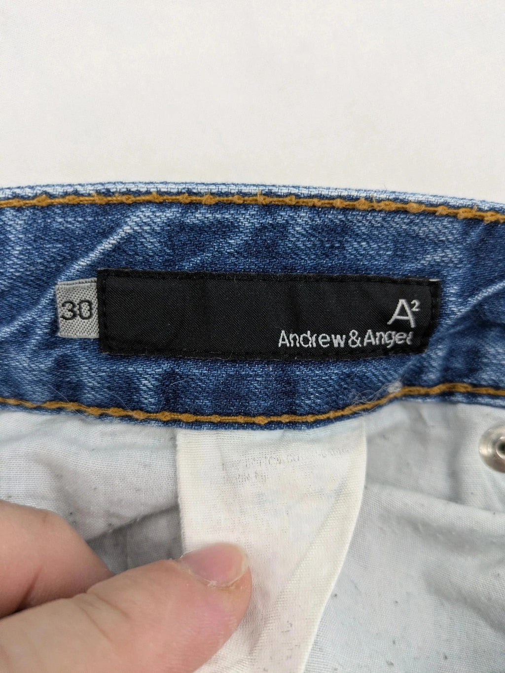 Andrew & Angel blue straight jeans distressed with red tartan patches and worn details.