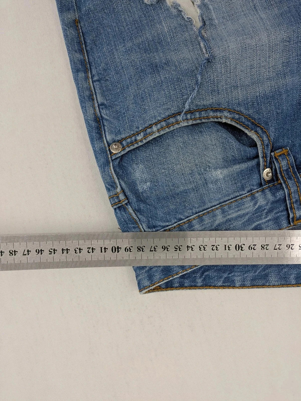 Andrew & Angel blue straight jeans distressed with red tartan patches and worn details.