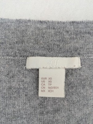 H&M grey cardigan with V-neck, button front, and layered ruffle sleeves.