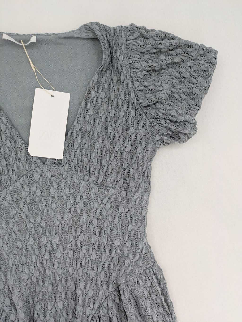 Zara grey mini dress with V-neck, puff sleeves, and textured fabric pattern.