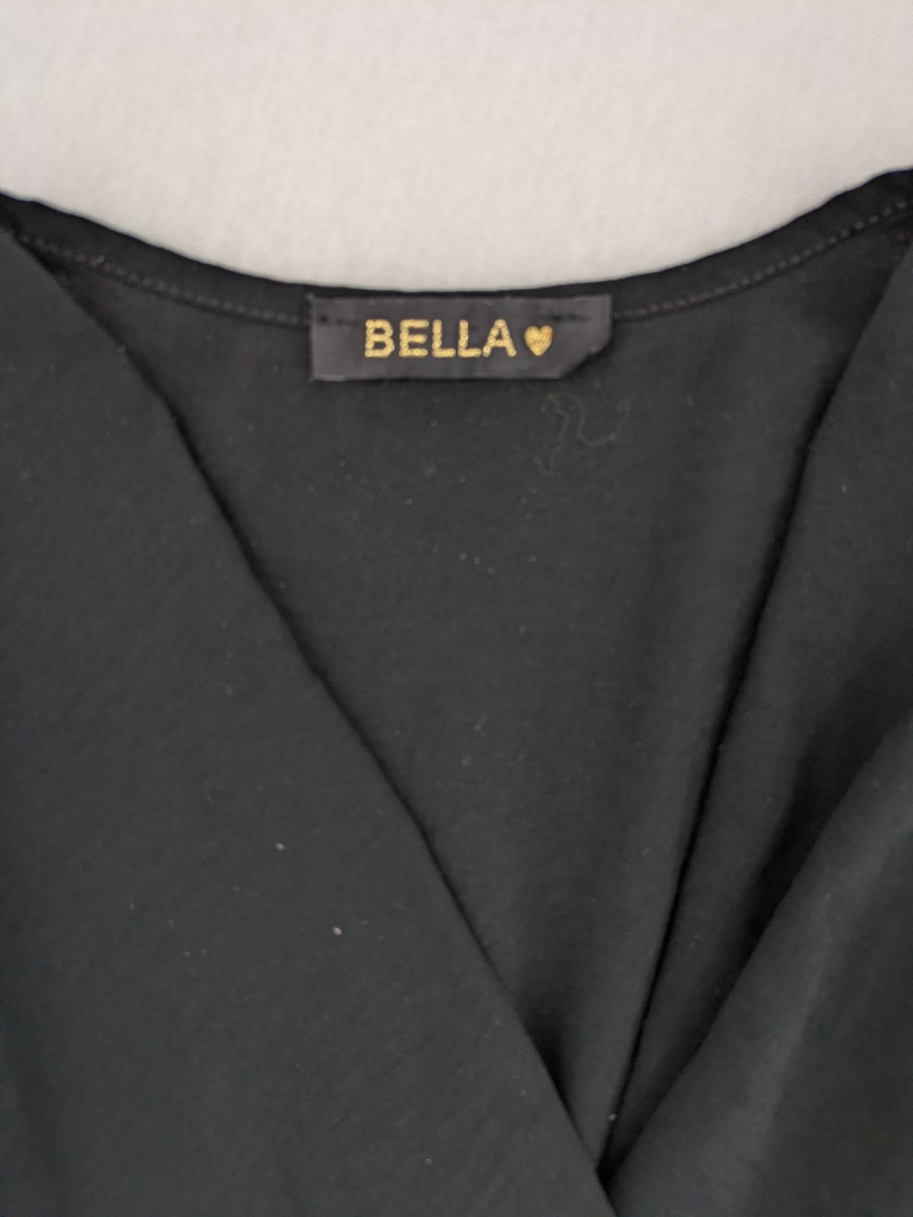 Bella black wrap blouse with deep V-neck and ruffled long sleeves.