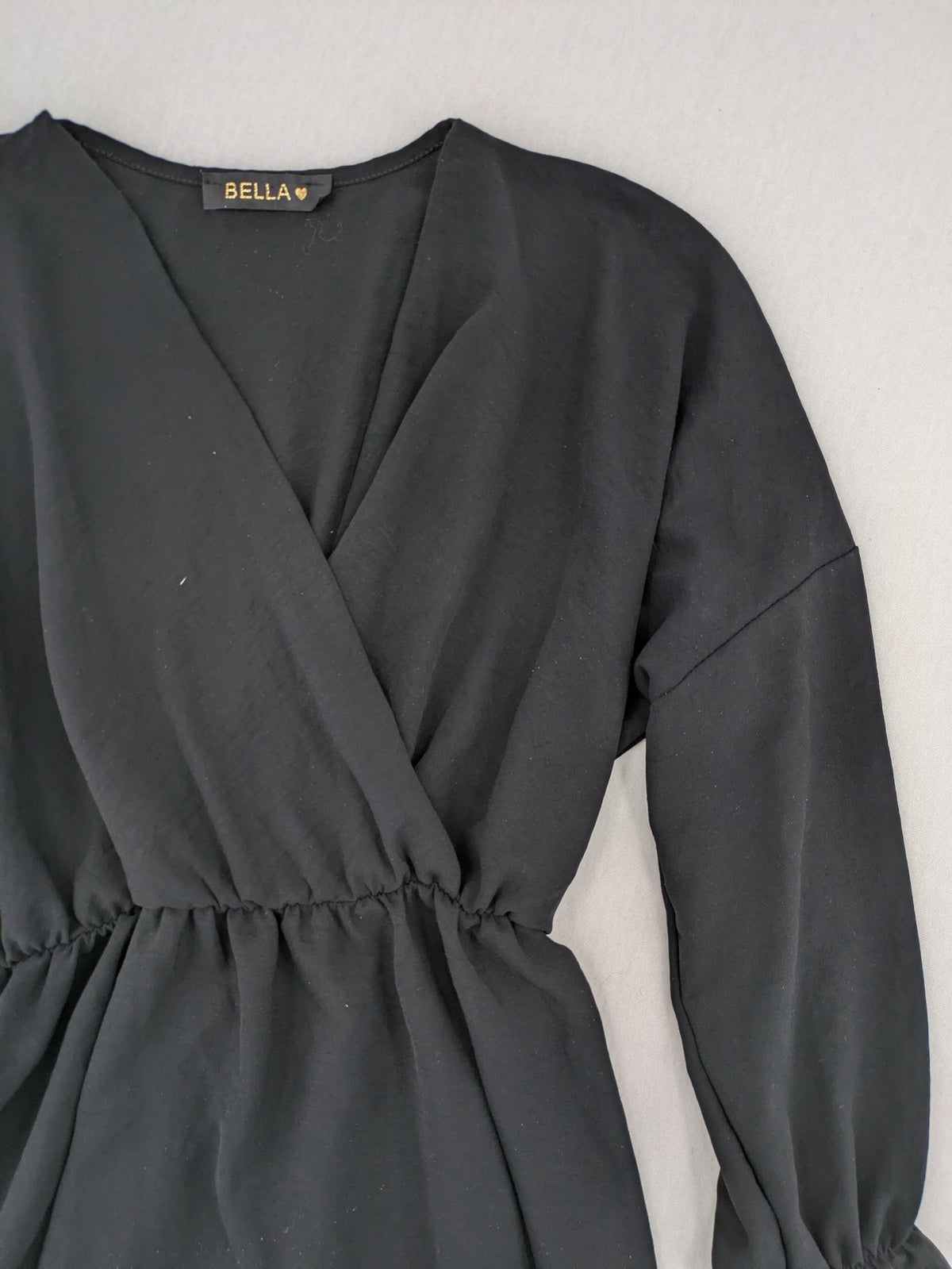 Bella black wrap blouse with deep V-neck and ruffled long sleeves.