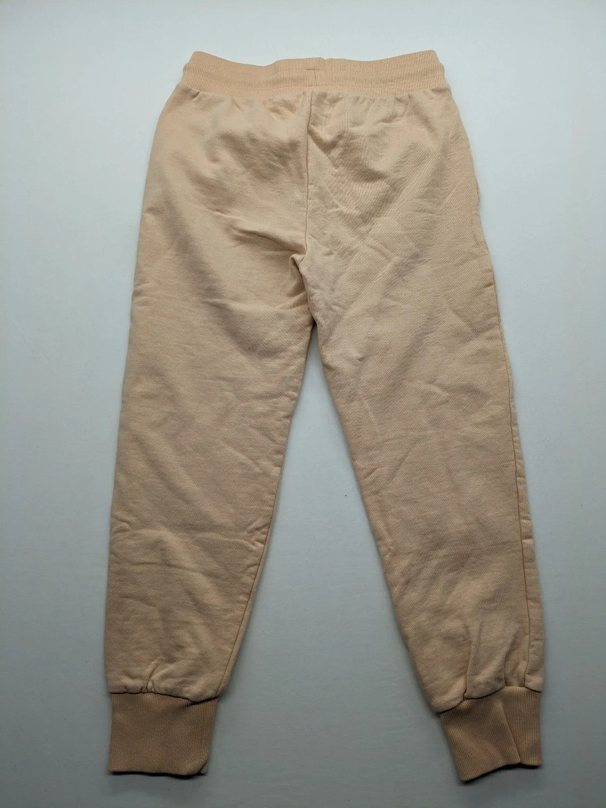 Hummel beige jogging pants with adjustable drawstring, embroidered logo, and ankle cuffs.