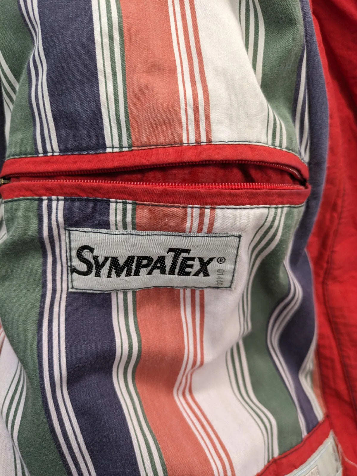 Bush Sportswear red trekking jacket with front zipper, multiple pockets, and striped lining.