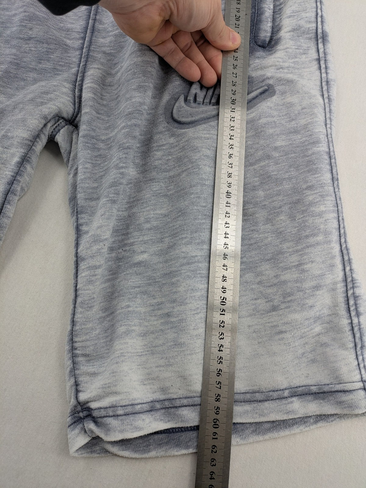 Nike grey acid wash jogger shorts with embossed logo and zip pockets.