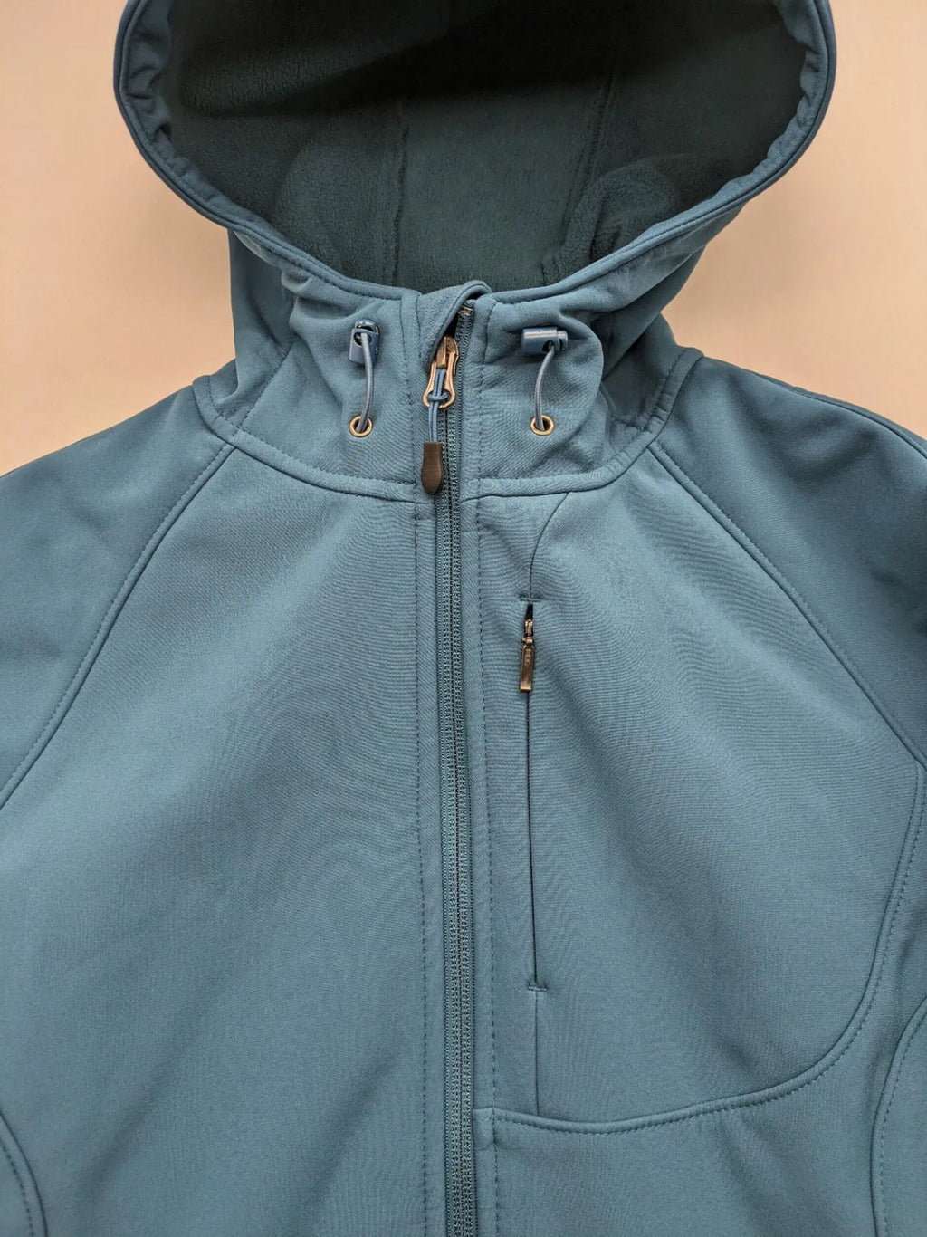 Kirkland Signature blue softshell jacket with hood, fleece lining, and zippered pockets.