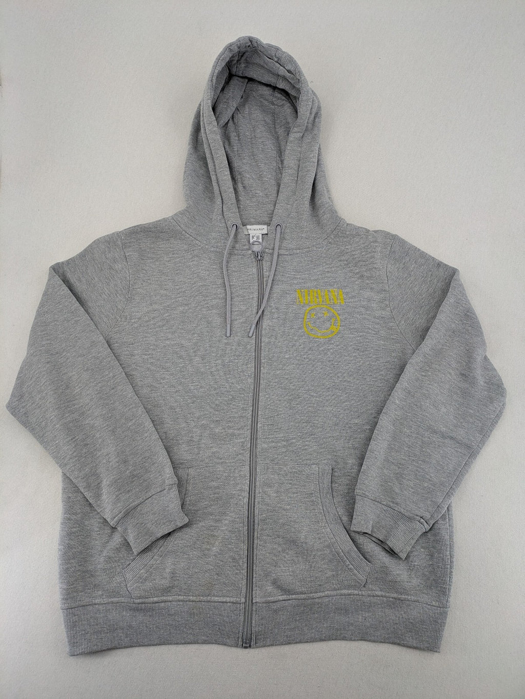 Primark grey zip-through hoodie featuring yellow Smiley logo and Nevermind graphic.