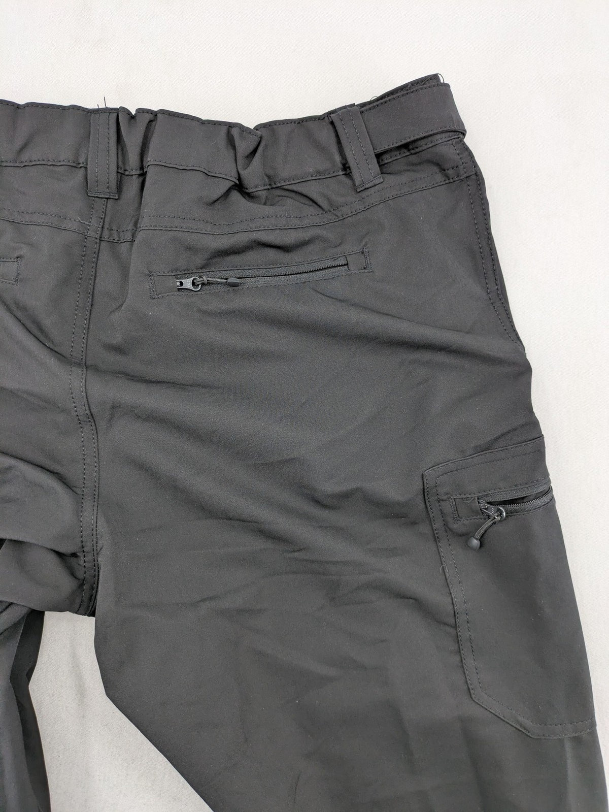 Outdoor grey trekking pants with zippered cargo pockets and durable stretch fabric.
