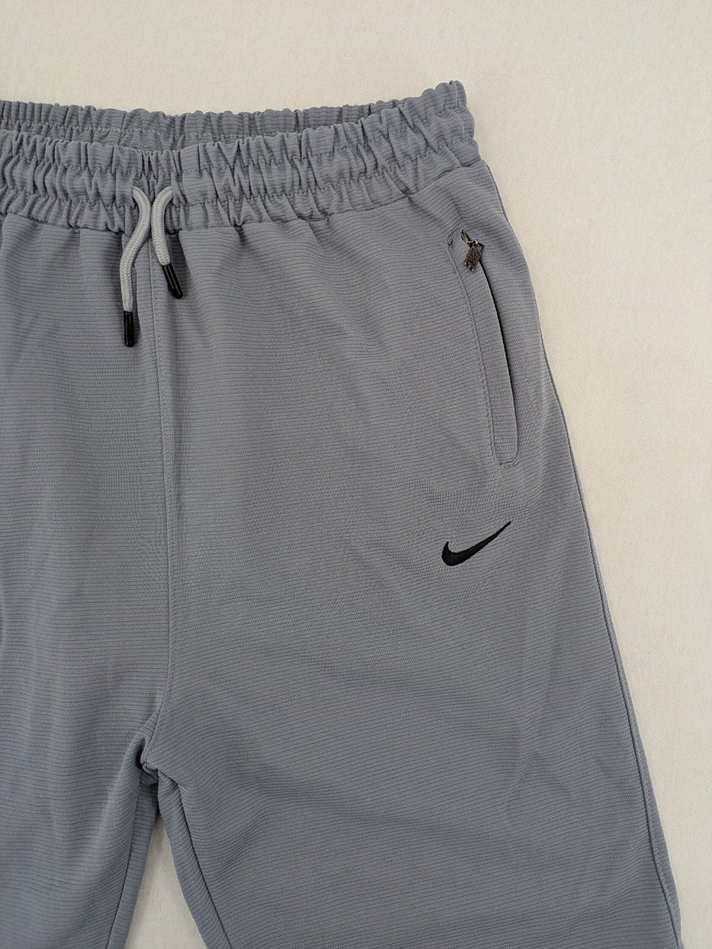 Nike grey shorts with Dri-FIT technology, elastic waistband, and zippered pockets.