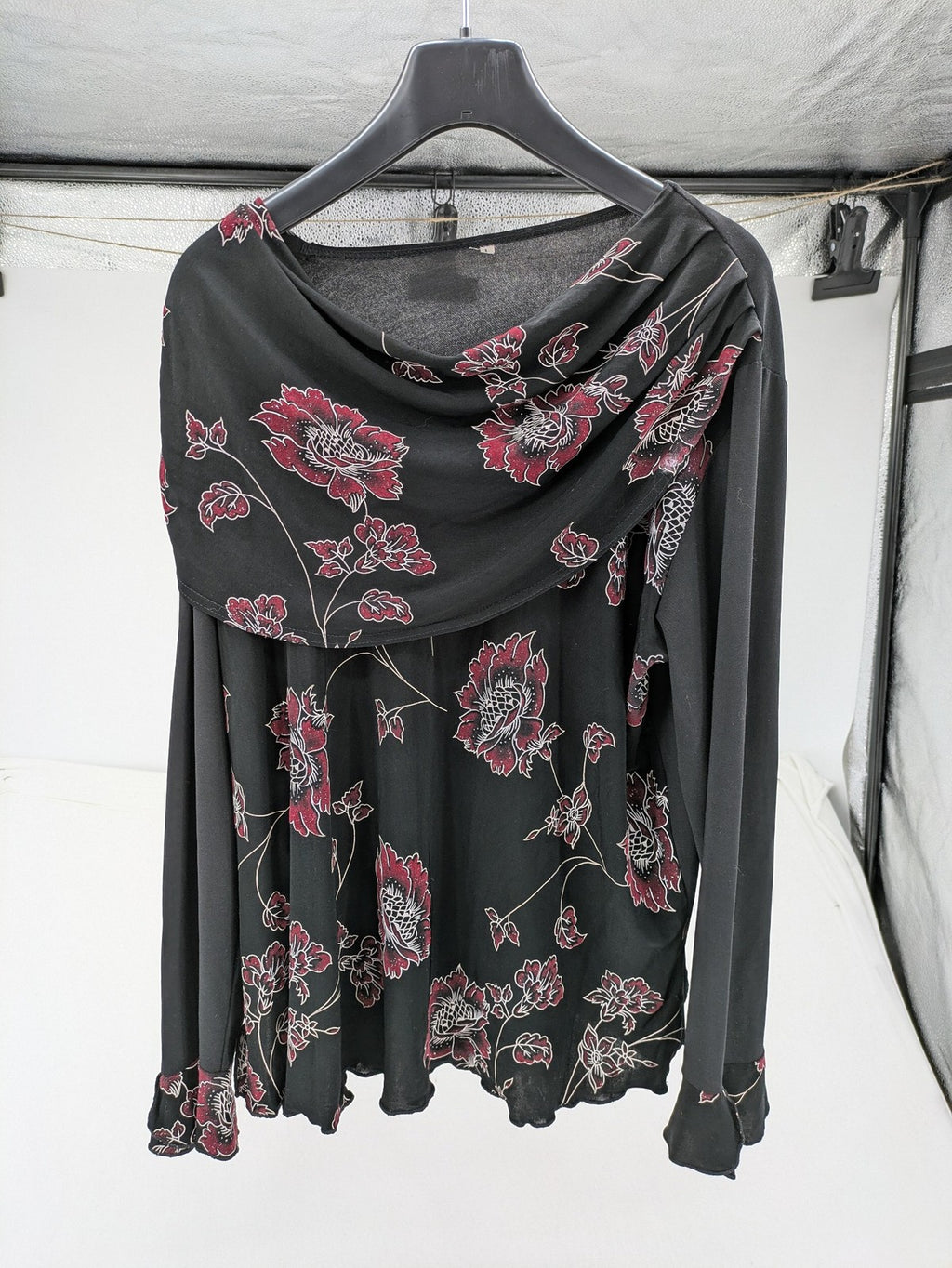 Damen black top with burgundy and white floral print, waterfall collar, and ruffled sleeves.