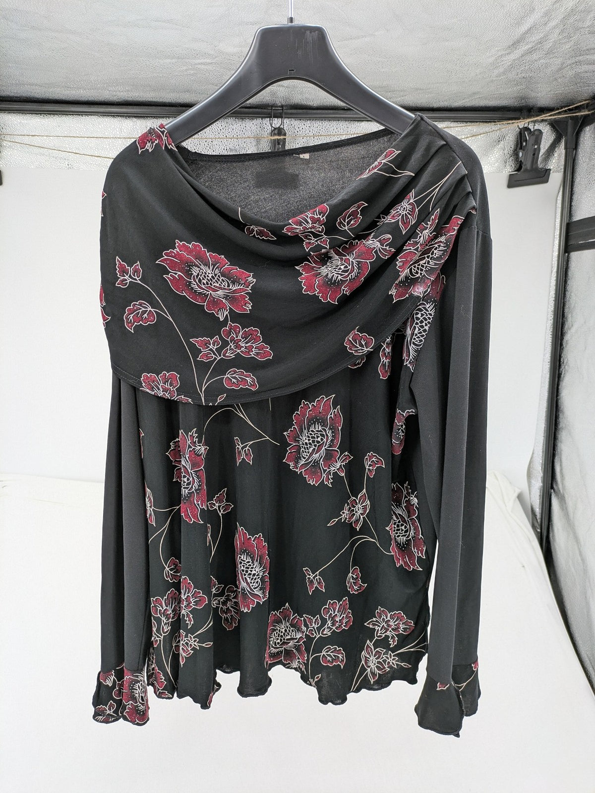Damen black top with burgundy and white floral print, waterfall collar, and ruffled sleeves.
