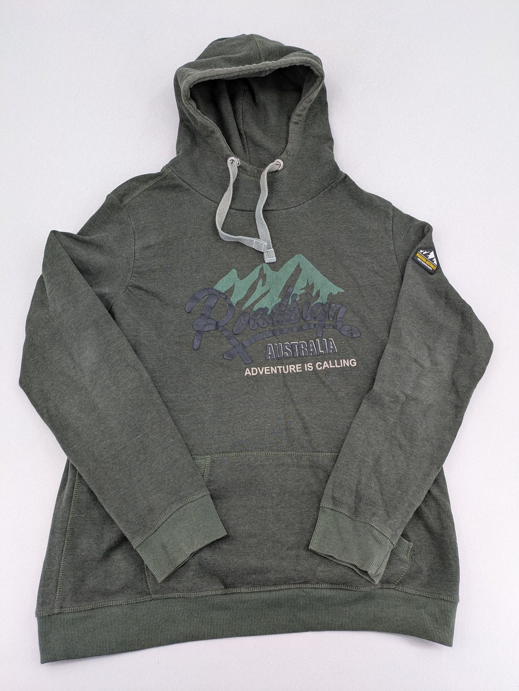 Roadsign Australia green hoodie with mountain graphic print and logo patch on sleeve.