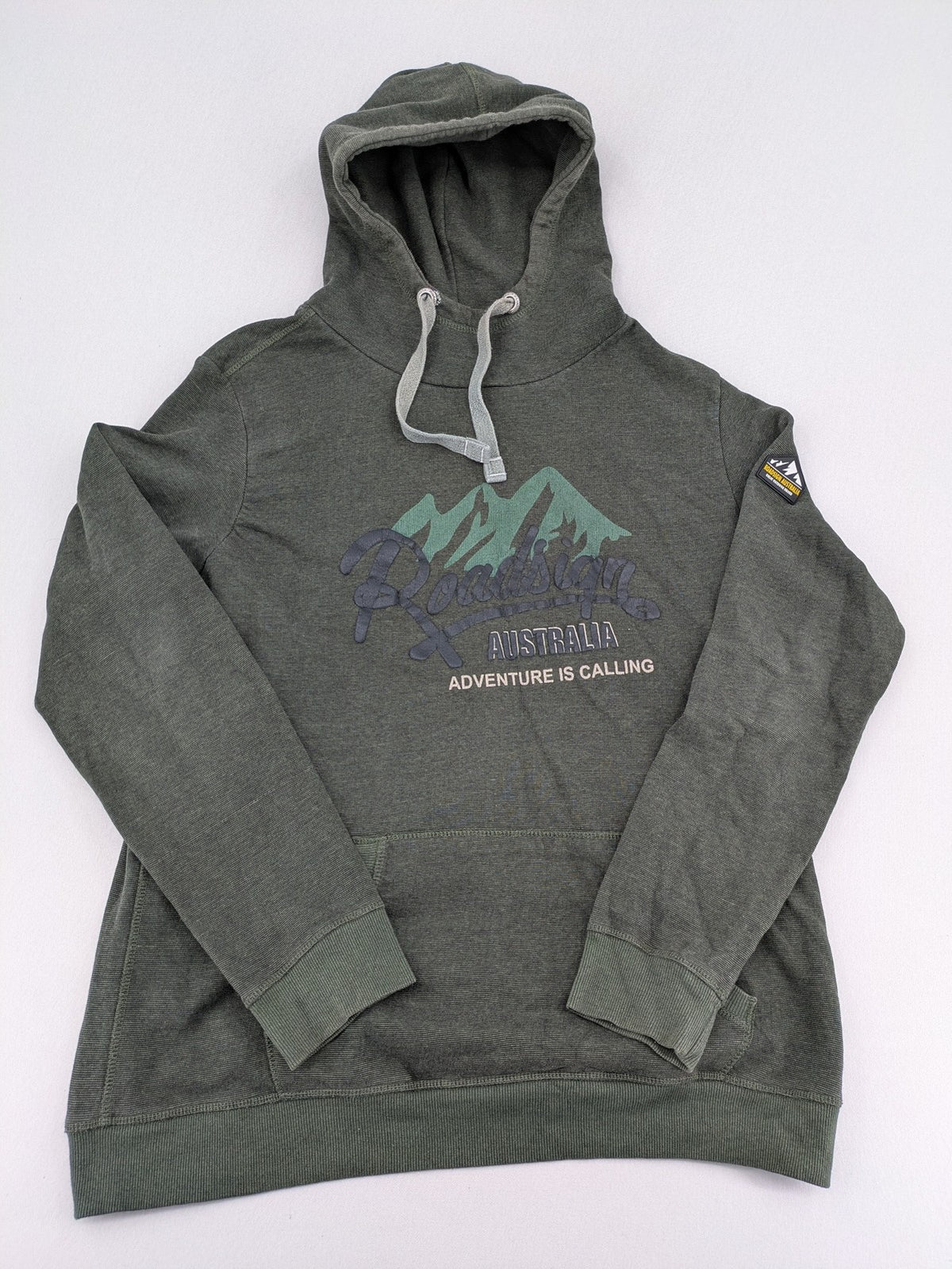 Roadsign Australia green hoodie with mountain graphic print and logo patch on sleeve.