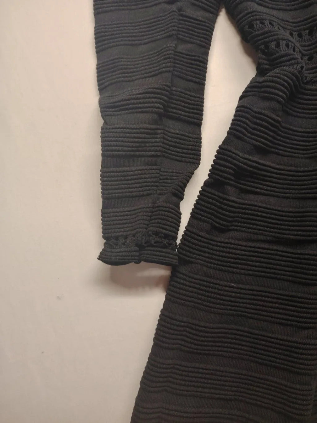 Supertuga black ribbed dress with V-neck, long sleeves, and pointelle detail at waist.