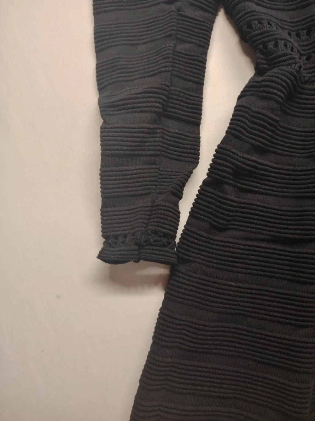 Supertuga black ribbed dress with V-neck, long sleeves, and pointelle detail at waist.