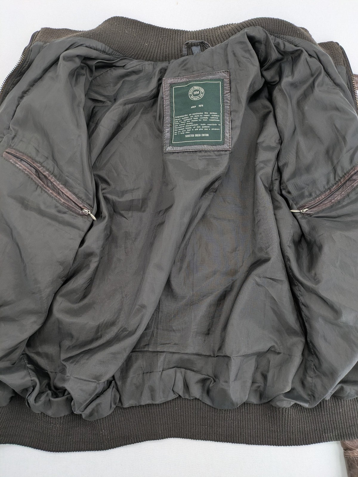 H&M green leather bomber jacket with ribbed collar and moto-style padding.