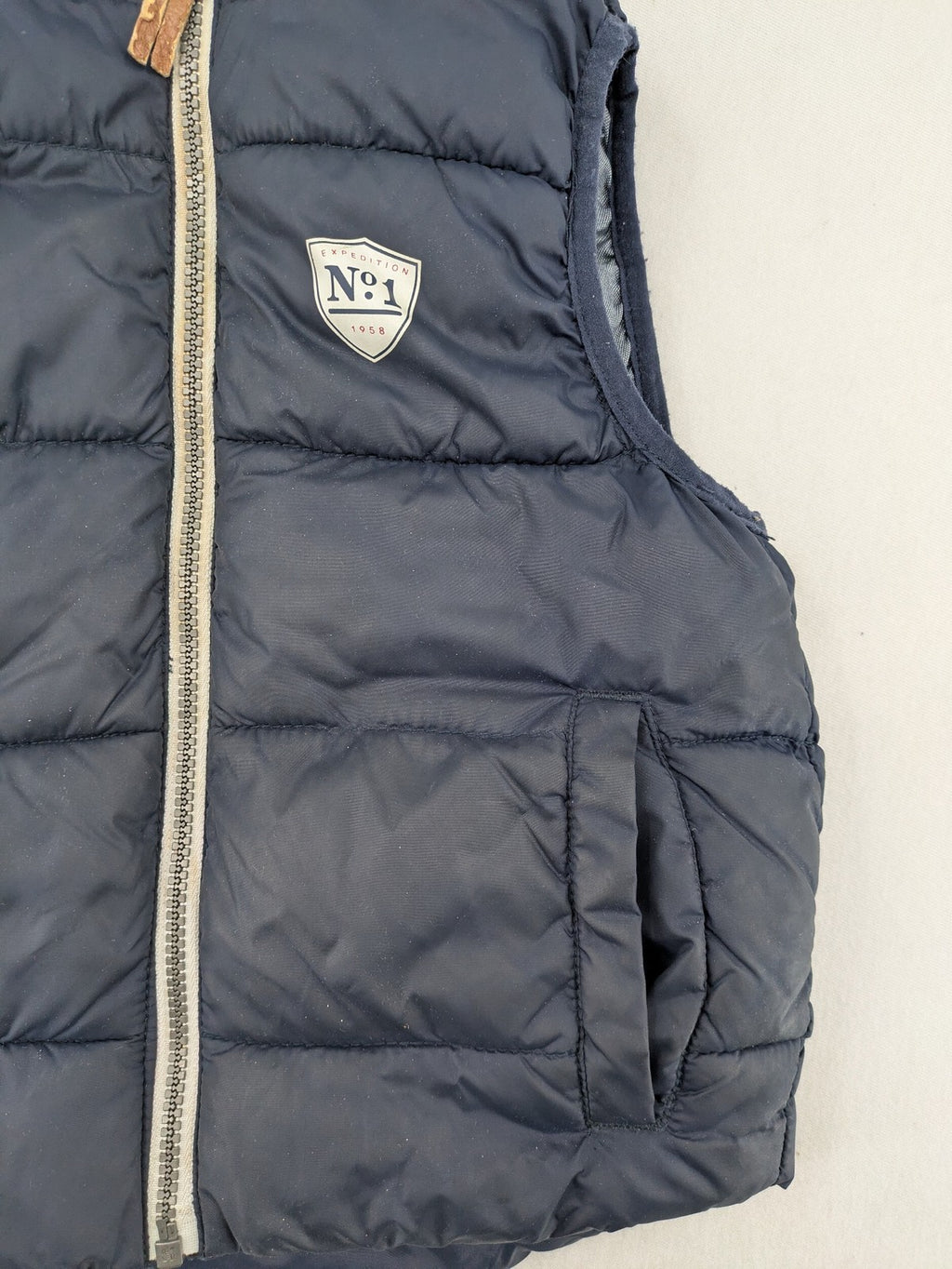 H&M navy puffer vest with grey hood and zip pockets for kids.