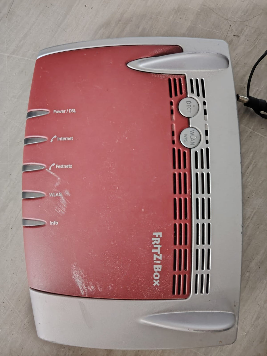AVM wireless router grey and red with NetCologne logo and multiple connectivity ports.
