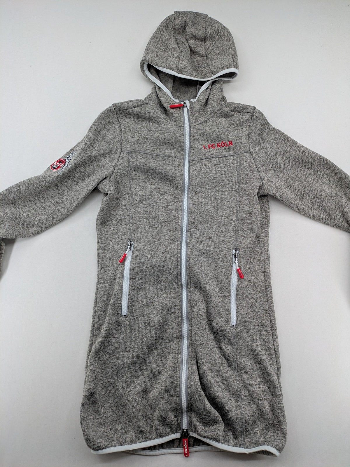 1. FC Köln grey fleece jacket with embroidered logo and hood, perfect for fans.