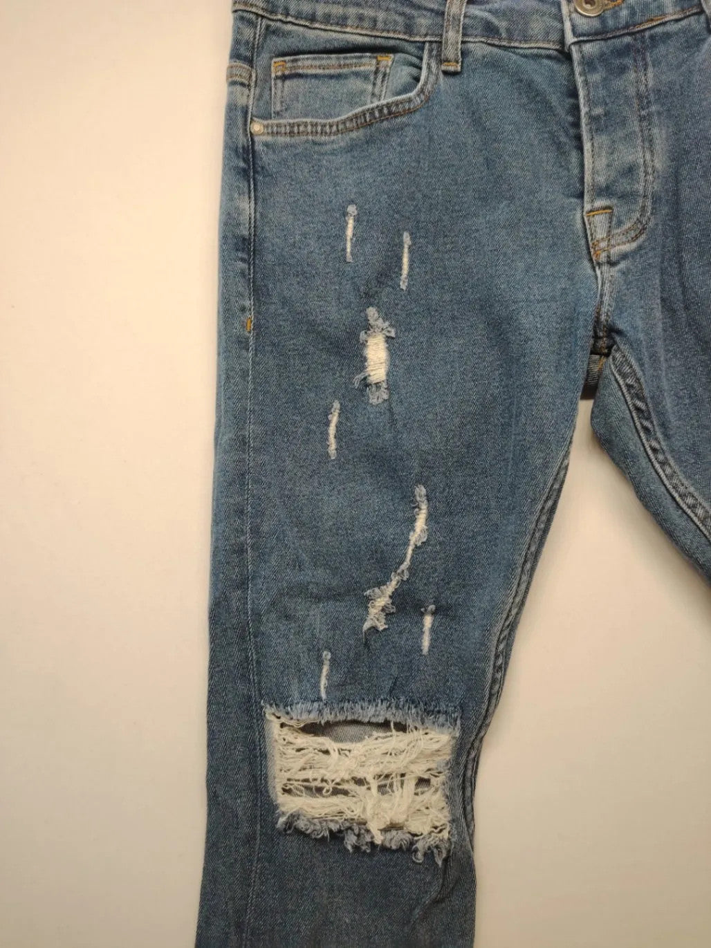 Damen blue skinny jeans with ripped details, five-pocket style, and classic button closure.