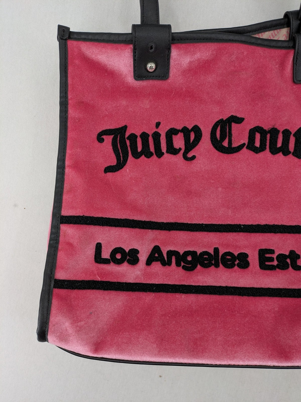 Juicy Couture pink velour handbag with oversized black logo and faux leather straps.