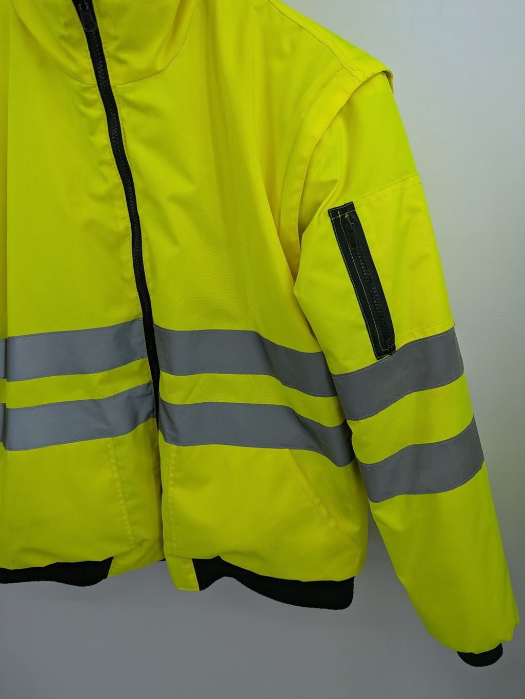 Hüren OHG grey and neon yellow safety jacket with reflective stripes and zippered arm pocket.