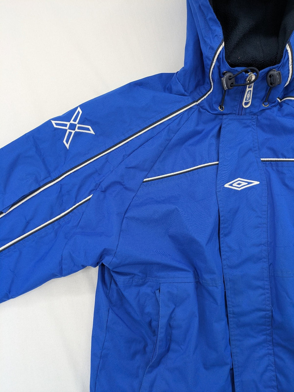Umbro blue fleece-lined jacket with hood, reflective details, and white piping.