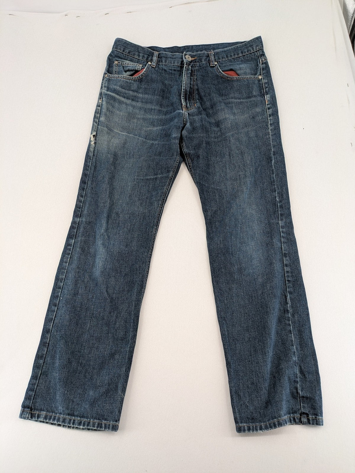 Indygo blue straight jeans 5-pocket style with subtle red pocket detail, cotton material.