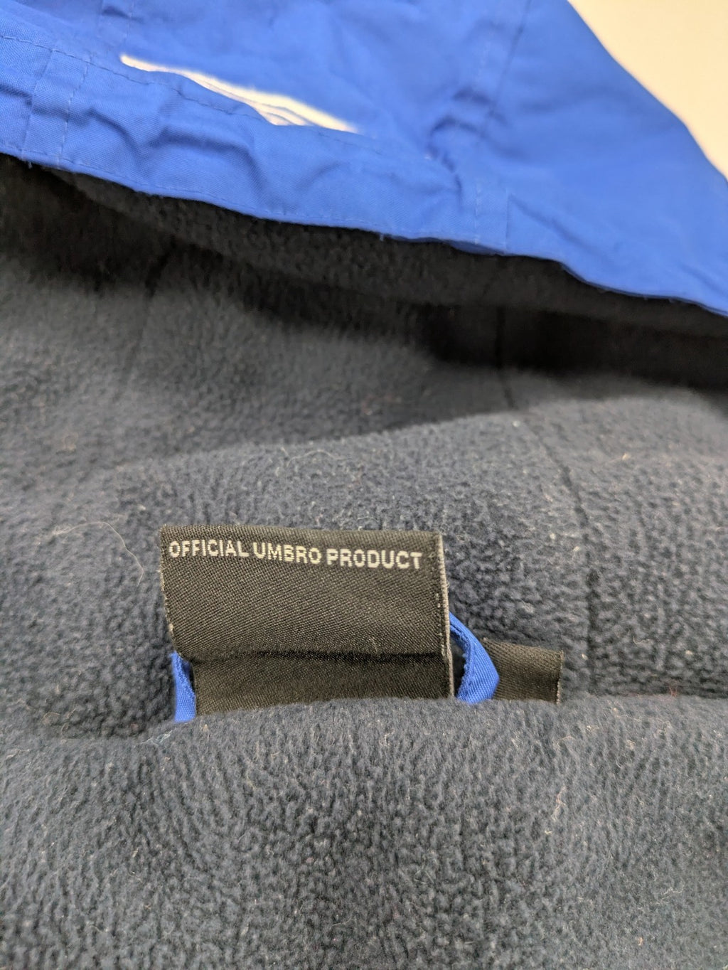 Umbro blue fleece-lined jacket with hood, reflective details, and white piping.
