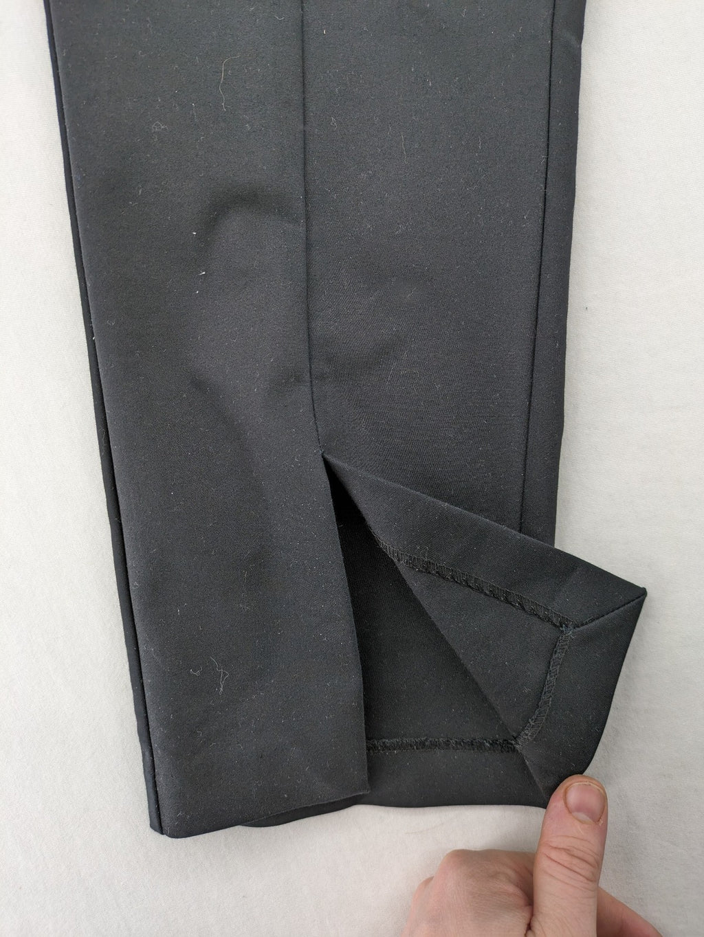 Zara black pants with front creases, subtle slit hem, and buttoned back pocket.