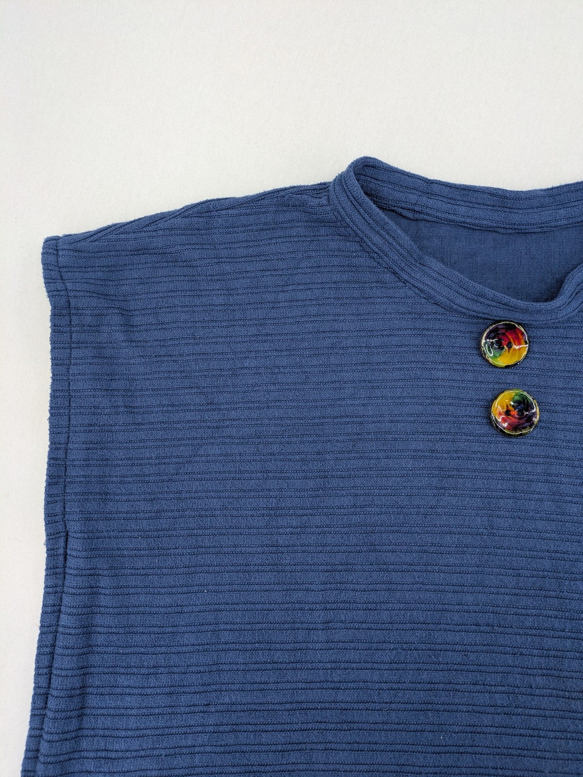Secondhand blue tank top with ribbed texture and colorful decorative buttons.