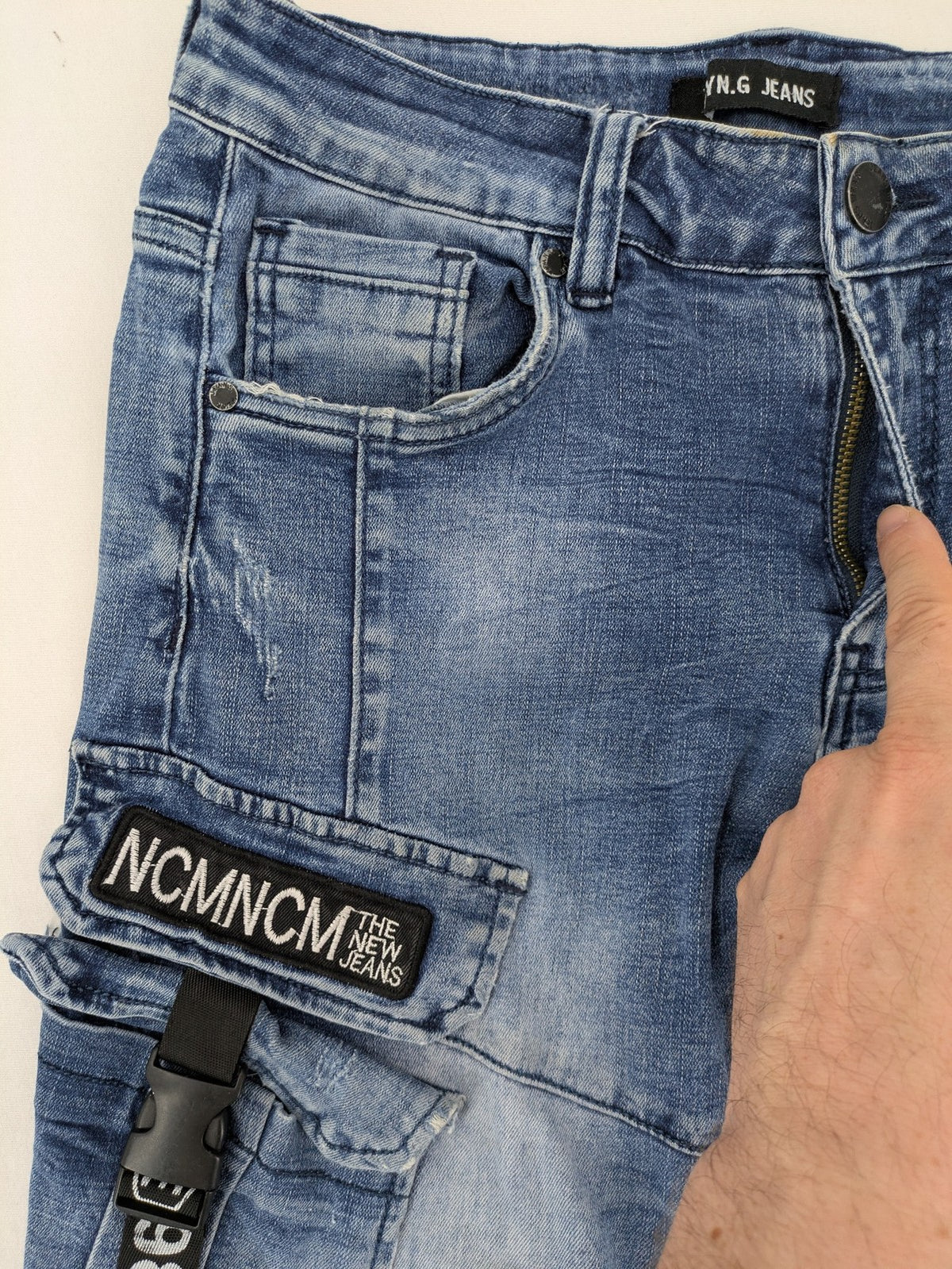 FN.G blue straight jeans with AC/DC patch, smiley face, and elastic jogger cuffs.