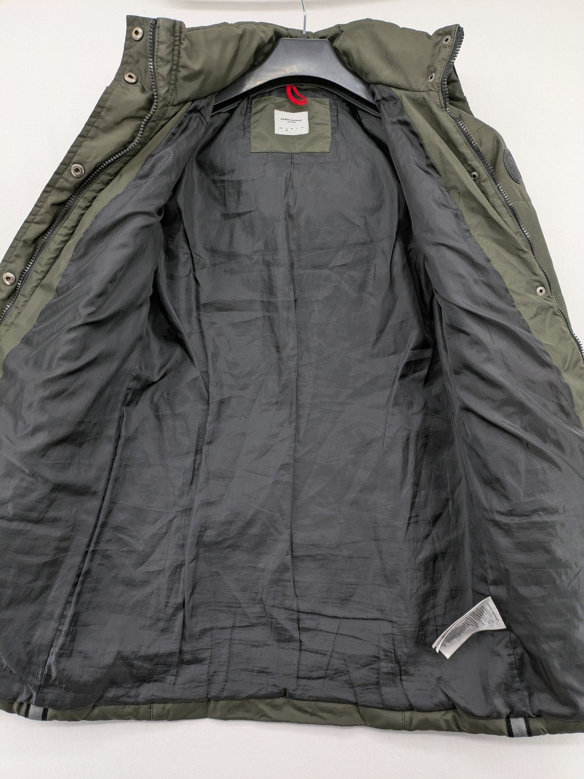 Vero Moda green puffer coat with quilted design and hood, featuring zipper and button closure.