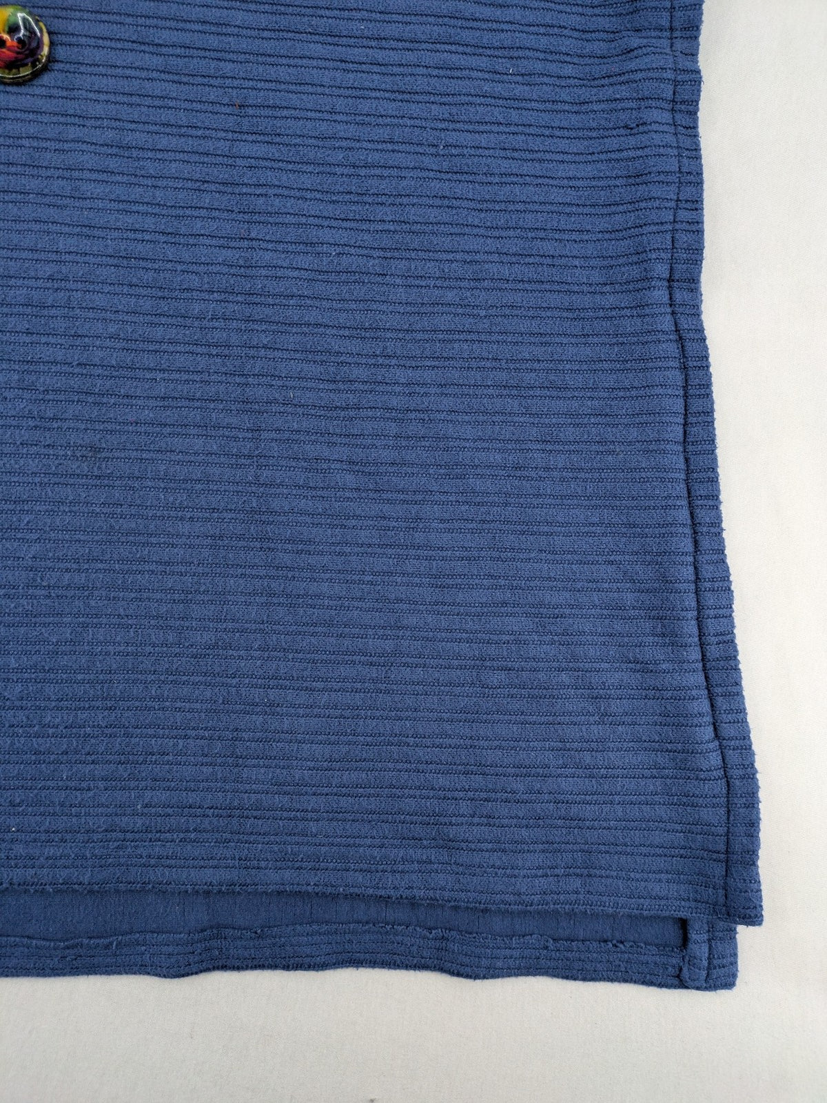 Secondhand blue tank top with ribbed texture and colorful decorative buttons.