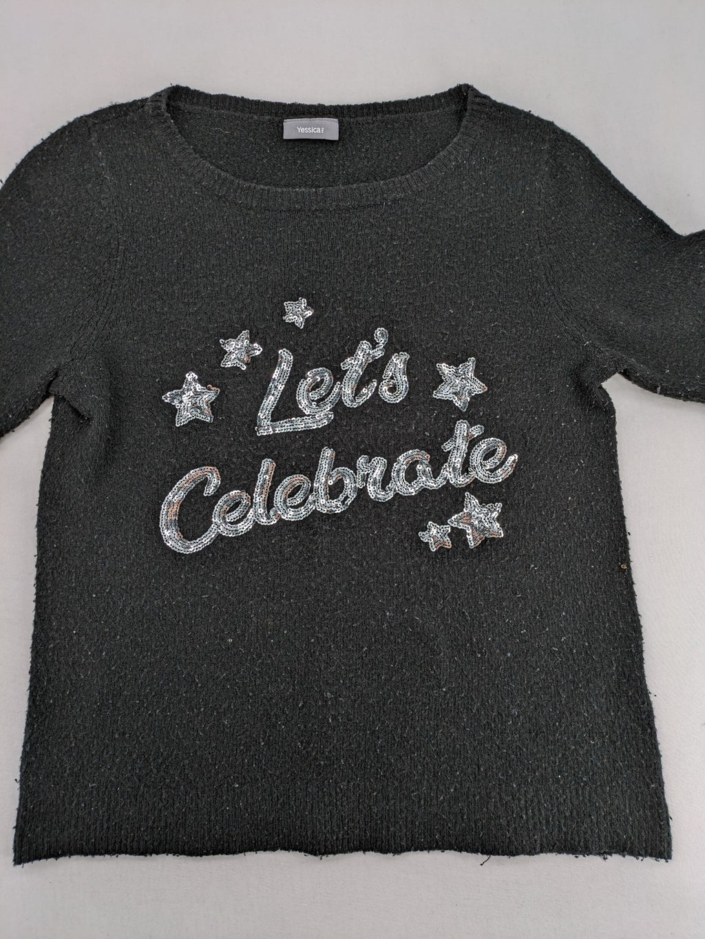 Yessica black turtle neck jumper with sequin "Let's Celebrate" graphic and star details.