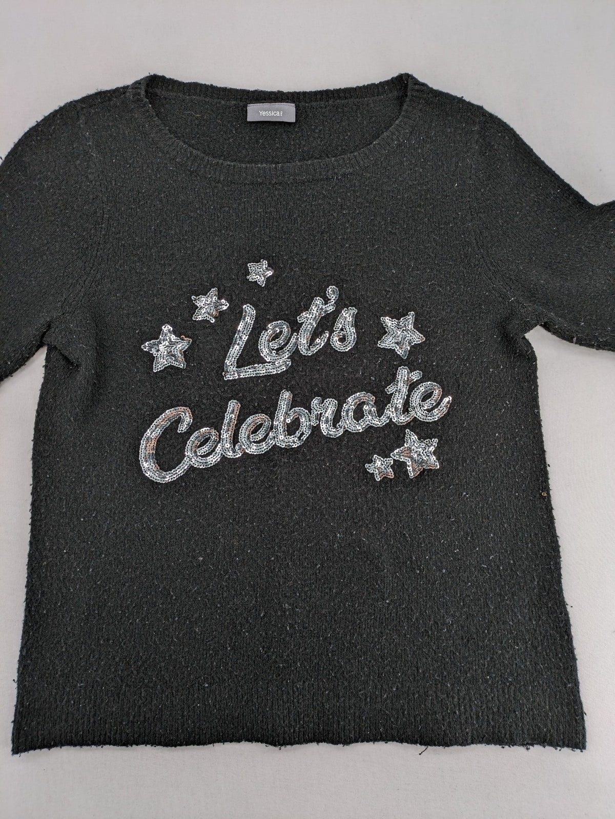Yessica black turtle neck jumper with sequin "Let's Celebrate" graphic and star details.