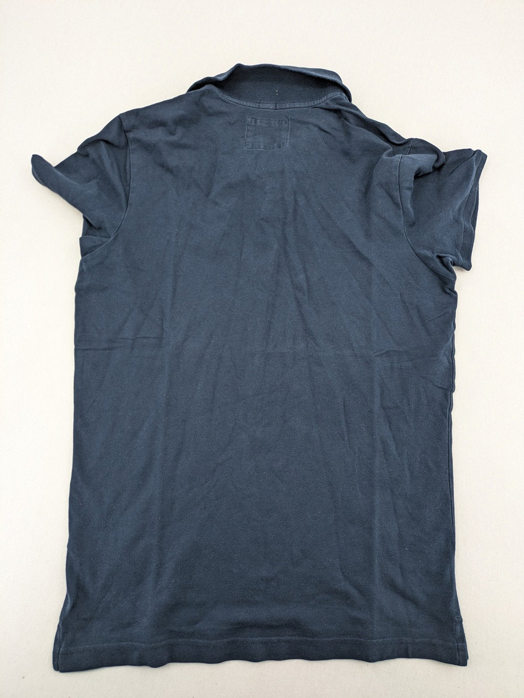 Hollister polo shirt navy blue with embroidered seagull logo and green trim.