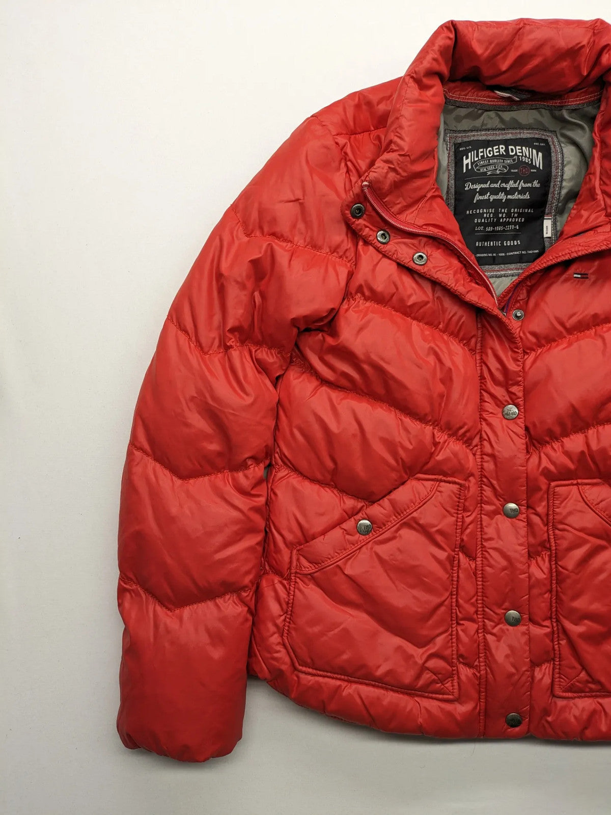 Hilfiger Denim red down jacket with quilted design, stand collar, and zip closure.