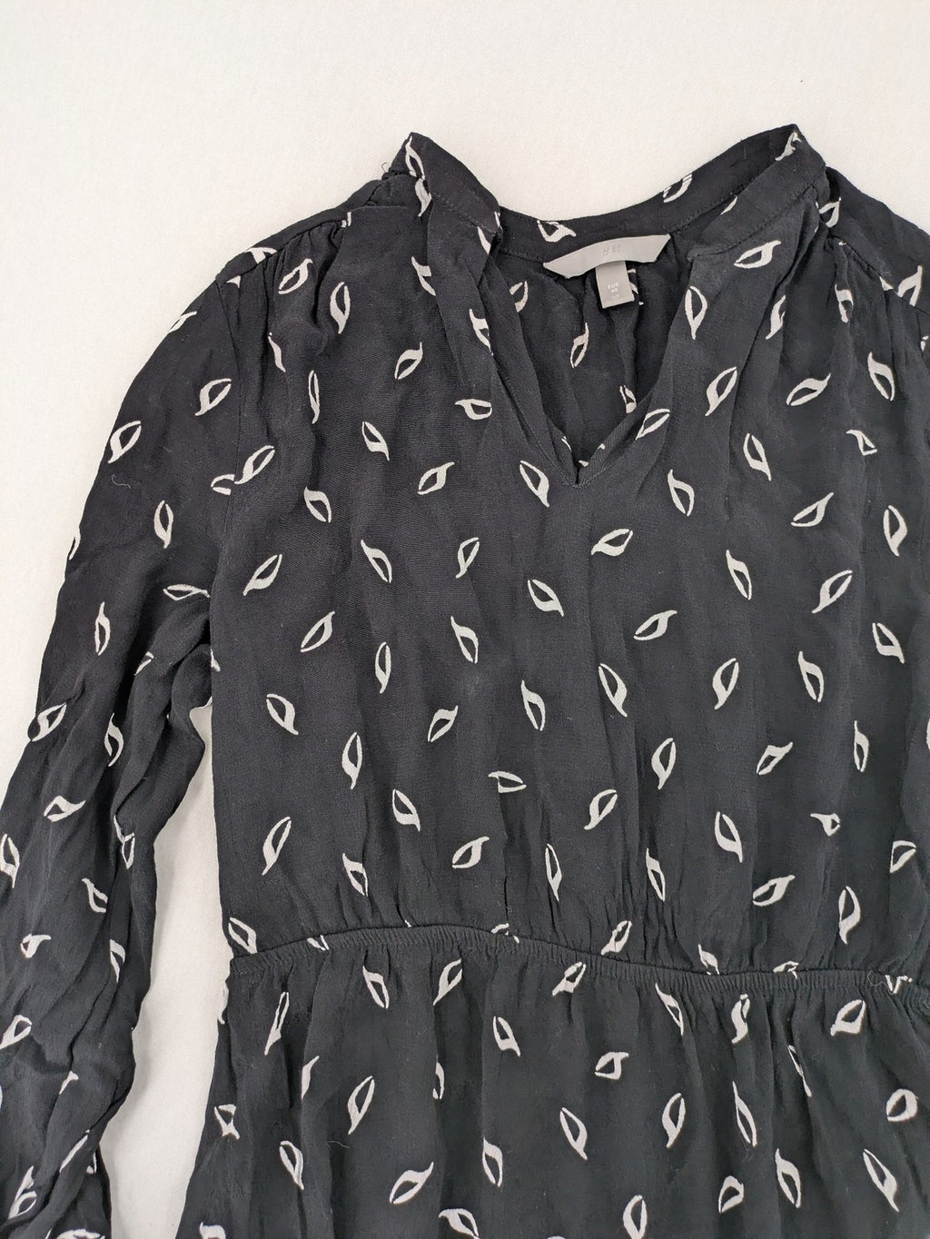 H&M grey and white dress with leaf print, V-neck, long sleeves, elastic cuffs.