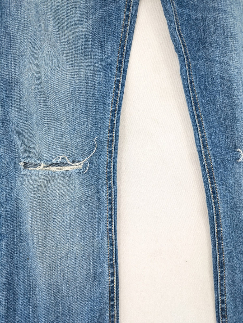 Tally Weijl blue bootcut jeans with distressed knees and raw hem detail.