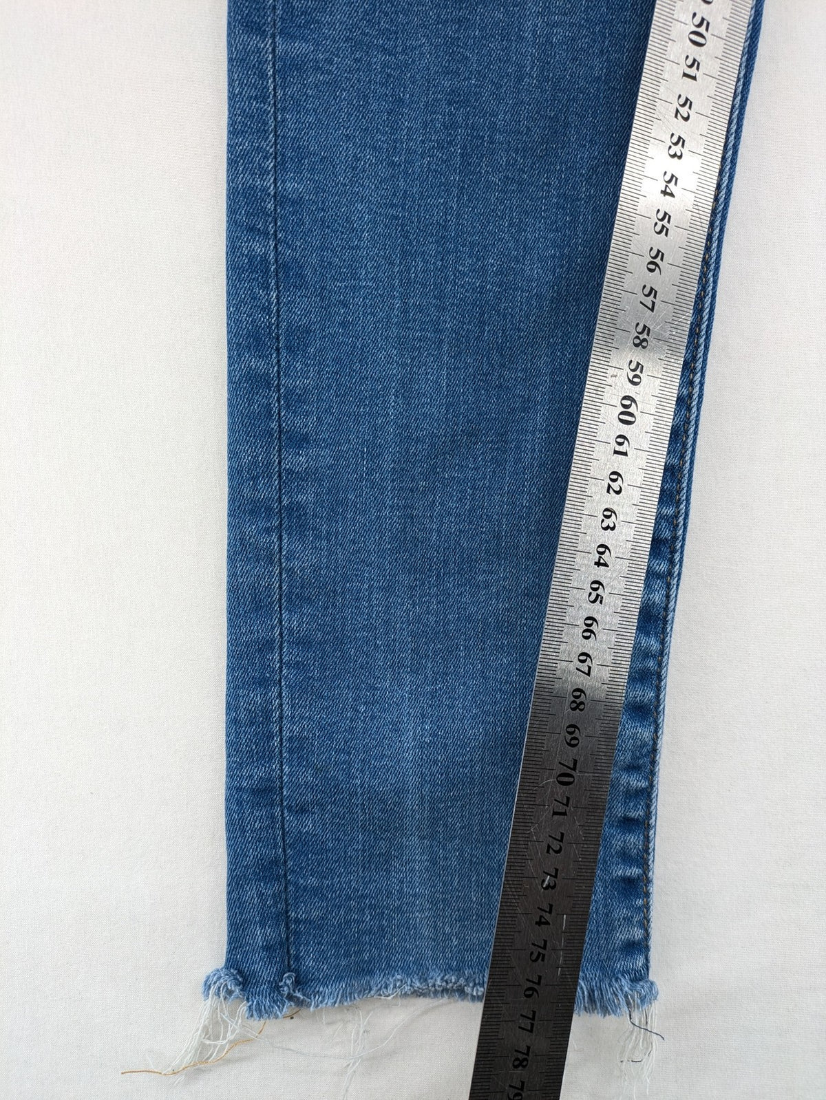 Levi's blue skinny jeans with raw hem, classic five-pocket design, and zip fly.