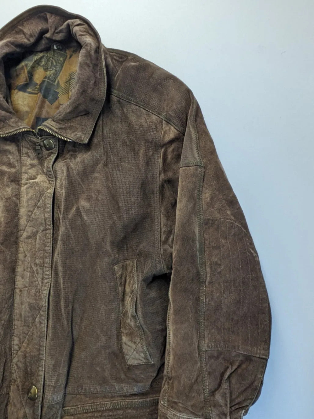 Vintage brown leather jacket with graphic lining, zip closure, and button placket.