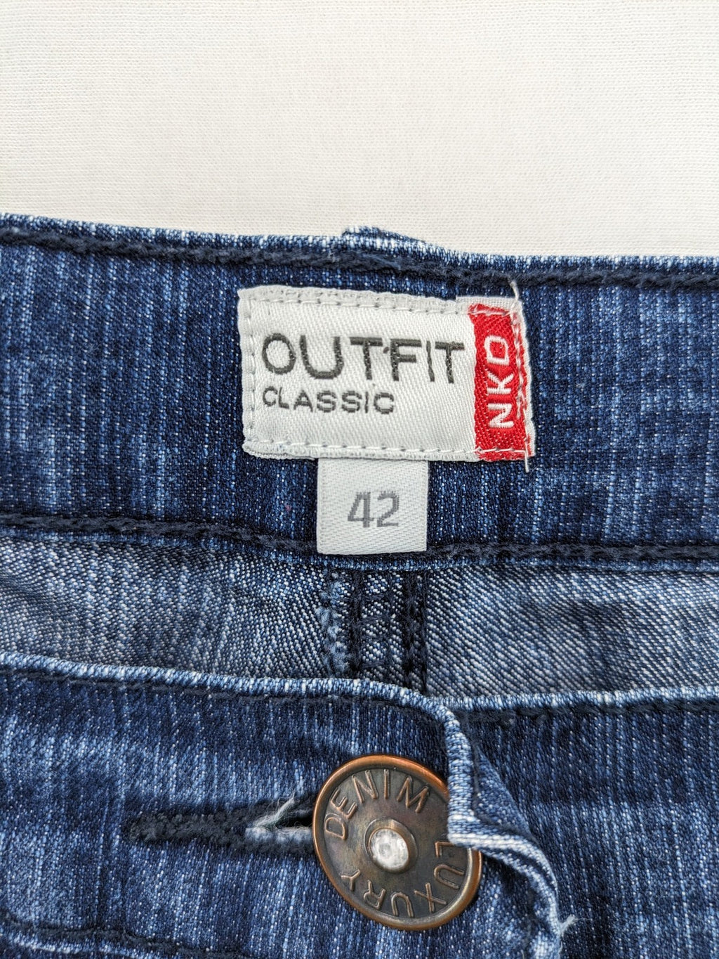 Outfit blue straight jeans with elastic waistband and embroidered crown-wing emblem on pockets.