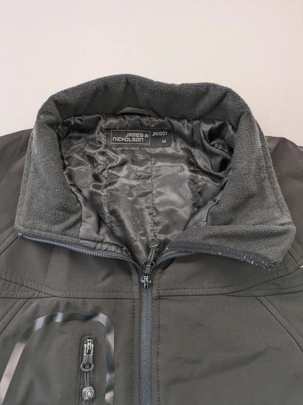 James & Nicholson grey softshell jacket with fleece lining and multiple zip pockets.