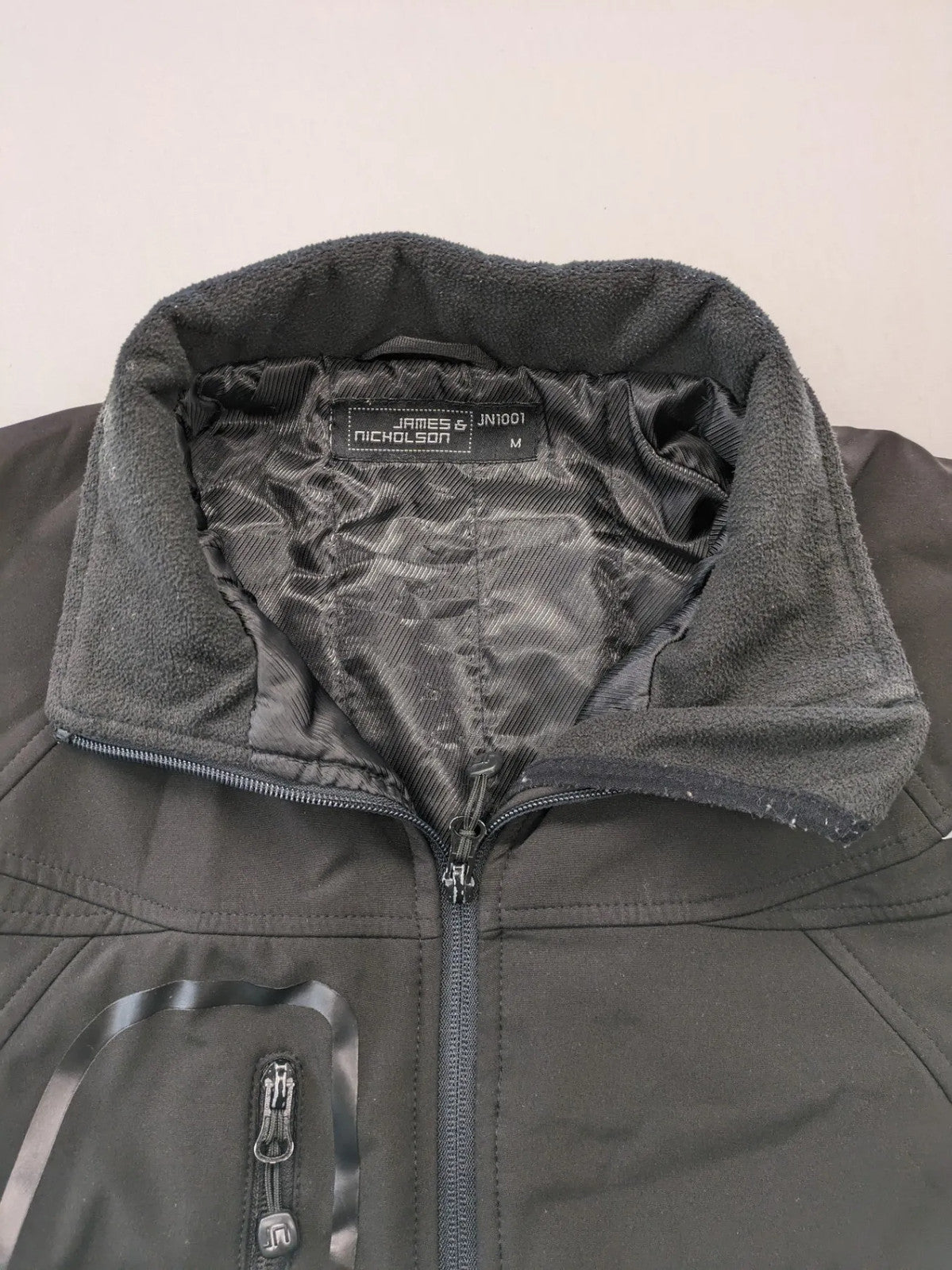 James & Nicholson grey softshell jacket with fleece lining and multiple zip pockets.