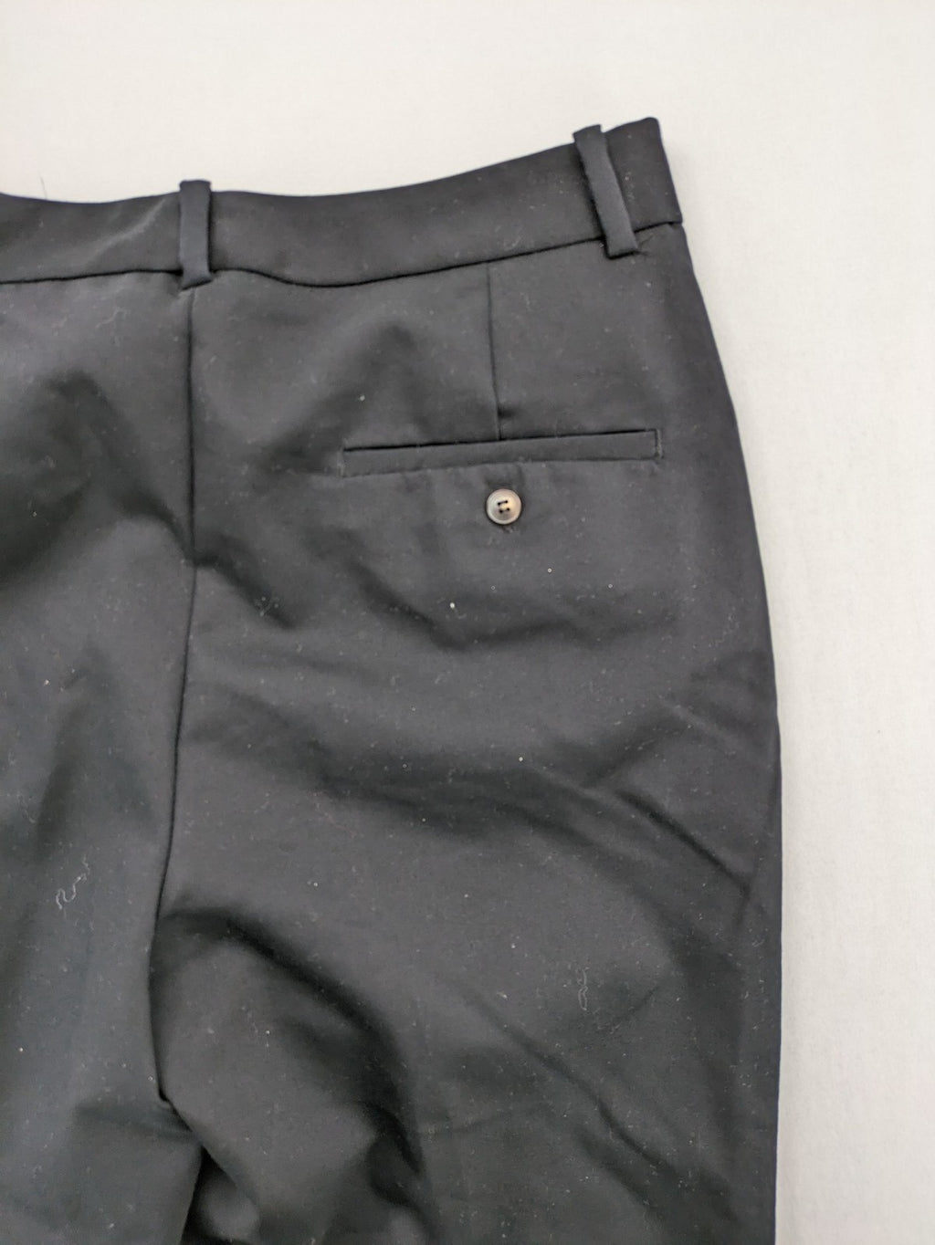 Zara black pants with front creases, subtle slit hem, and buttoned back pocket.