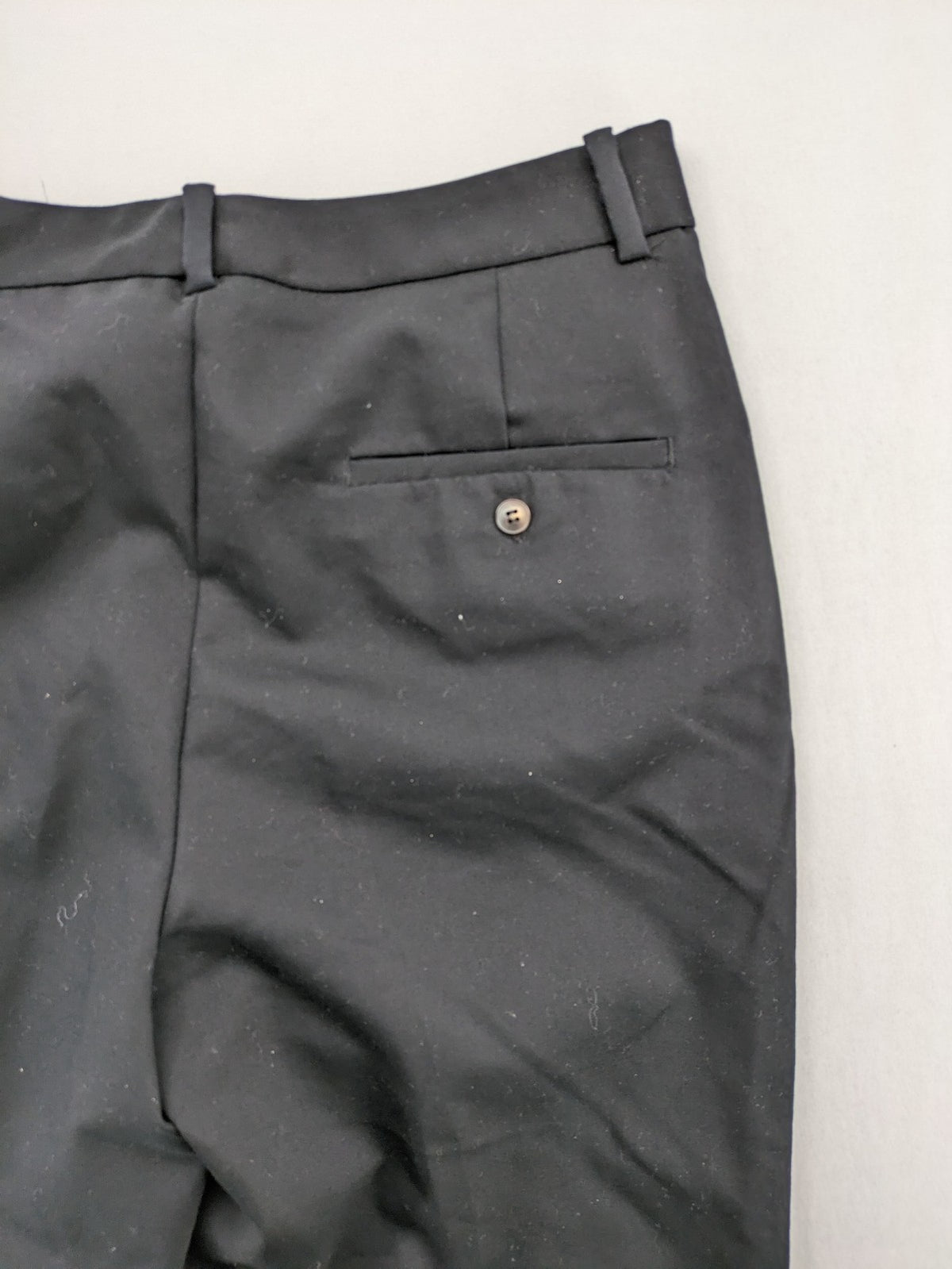 Zara black pants with front creases, subtle slit hem, and buttoned back pocket.